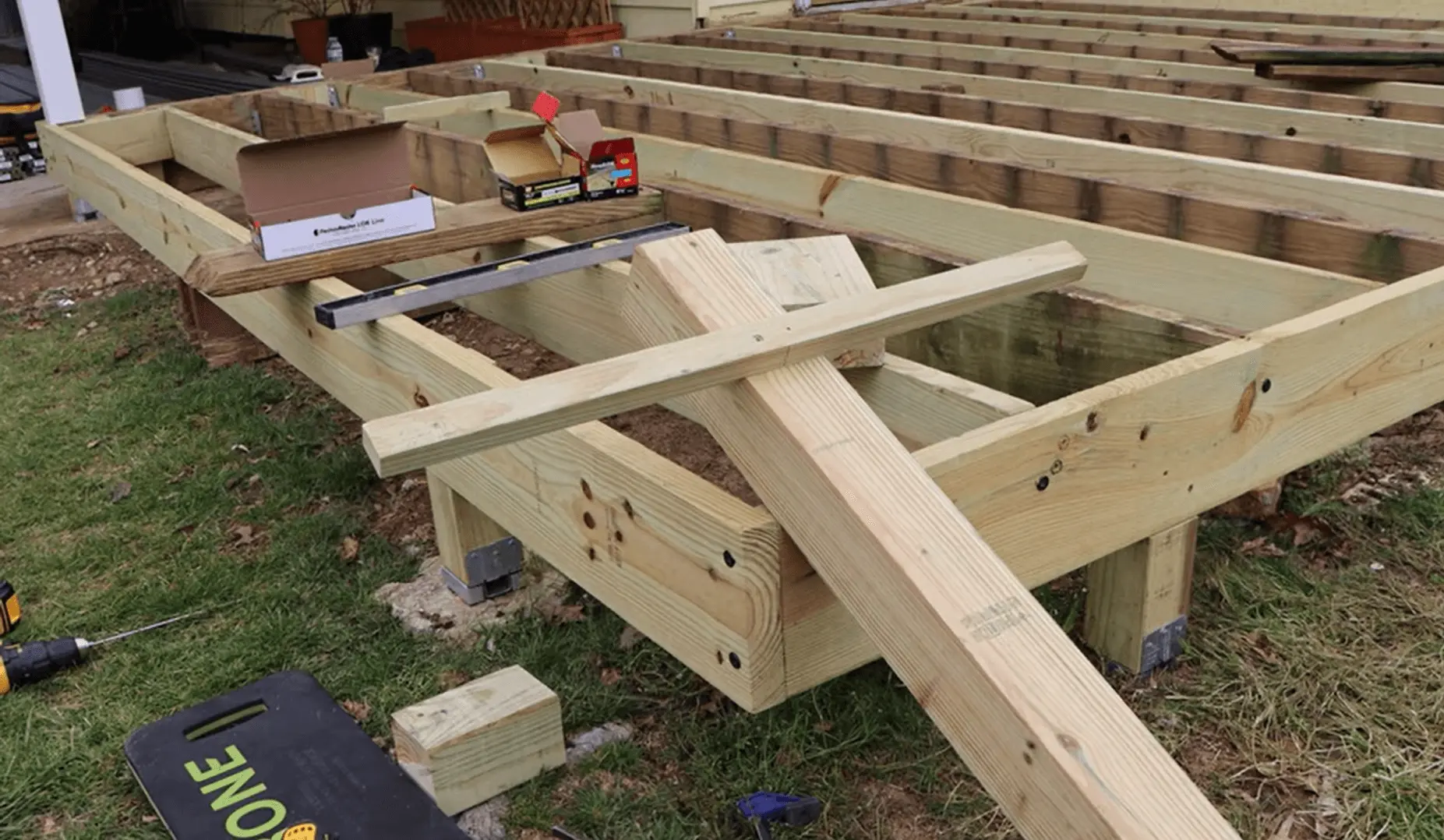 A contractor working on the framework of a wooden deck, carefully aligning the boards for a perfect fit. Ready to build your dream deck? Hire a professional contractor today for expert results!